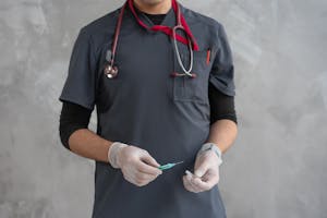 Healthcare worker with stethoscope holding a syringe ready for injection.